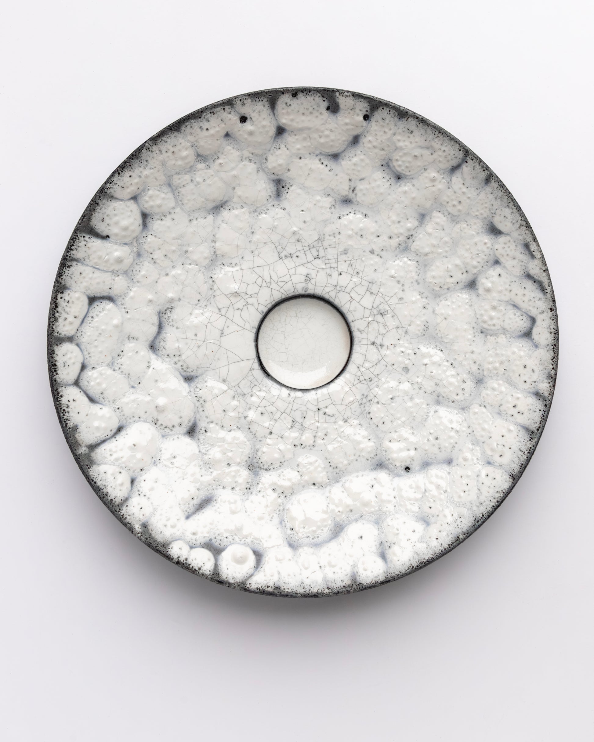 Round ceramic plate with textured surface on a white background