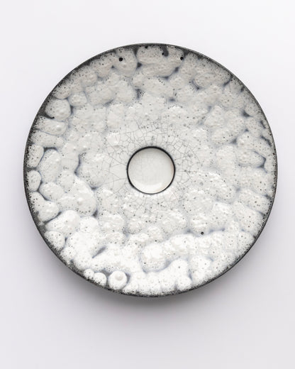 Round ceramic plate with textured surface on a white background
