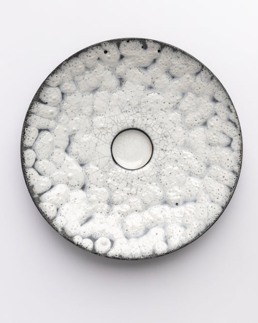Round ceramic plate with textured surface on a white background